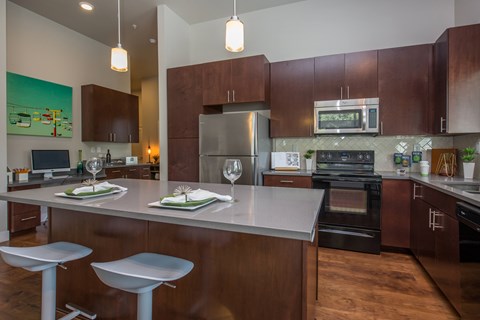 A modern kitchen with dark wood cabinets and stainless steel appliances.