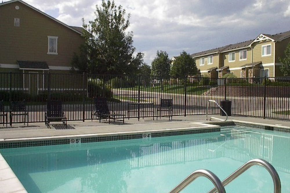 a swimming pool with chairs and a fence around it