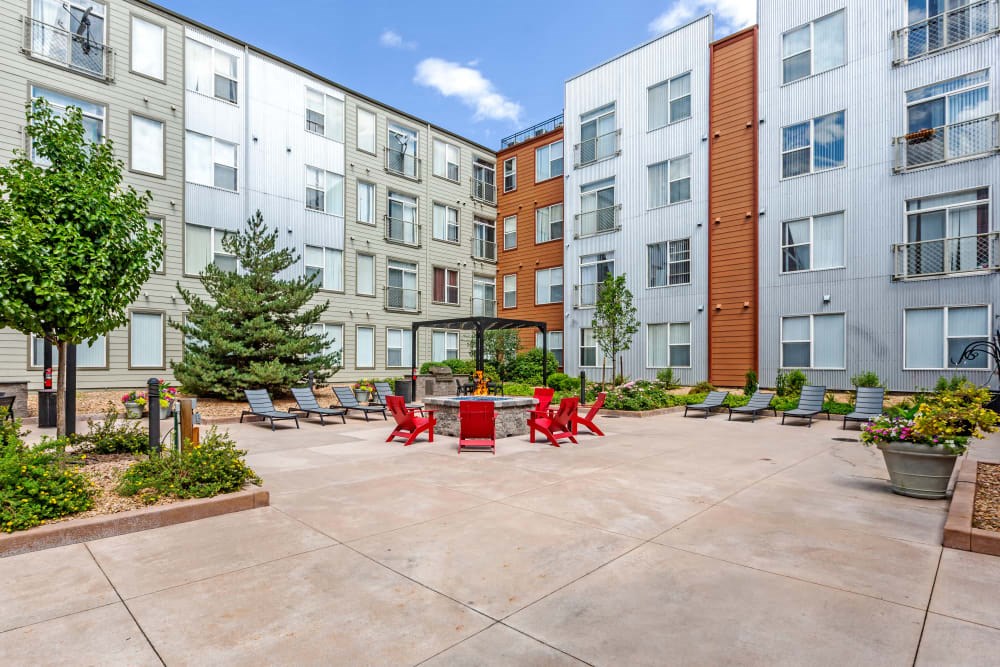 an outdoor courtyard with red chairs and benches in front of an apartment building