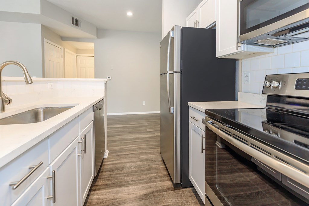 A black refrigerator in a kitchen with white cabinets.