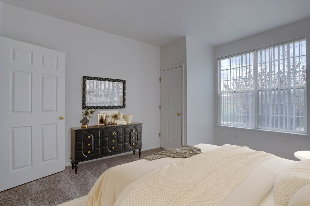 A bedroom with a bed, dresser, and window.
