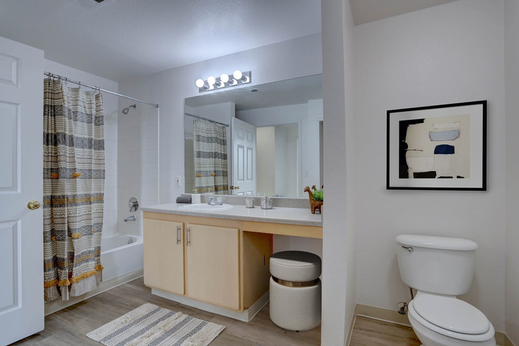 A bathroom with a toilet, sink, and mirror.