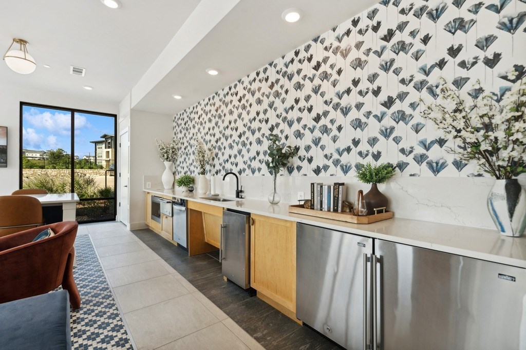 Clubhouse kitchen with a patterned wallpaper and stainless steel appliances.