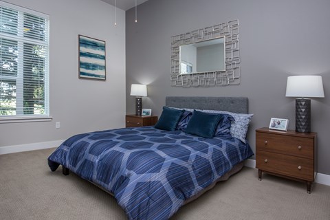 A bedroom with a bed, nightstand, and a mirror.