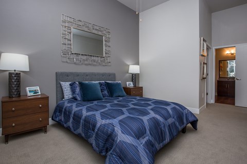 A bedroom with a bed, nightstands, and a mirror on the wall.