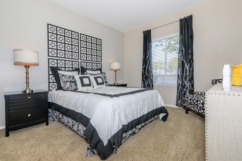 A bedroom with a large bed and a black and white patterned wall hanging.