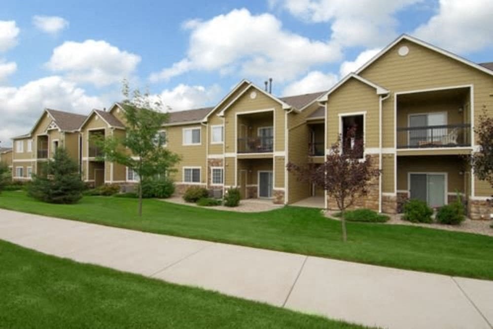 an apartment building with a sidewalk and green grass