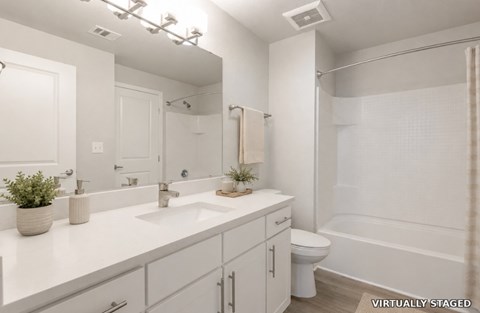 A white bathroom with a toilet, sink, and mirror.