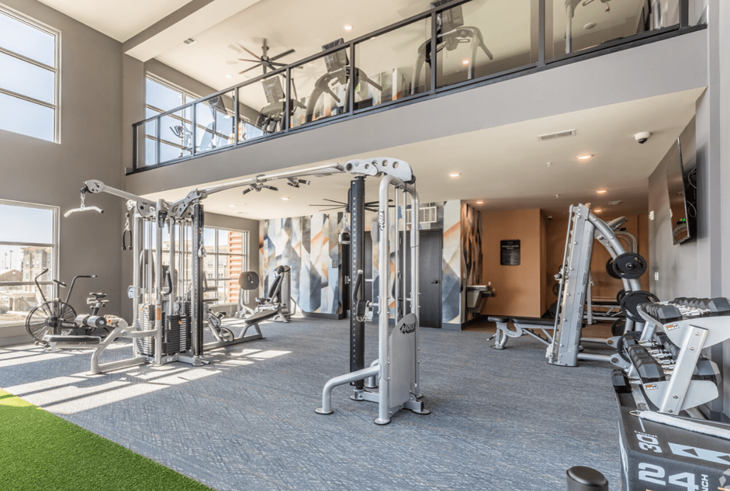 A gym with a variety of equipment including treadmills, weights, and exercise machines.