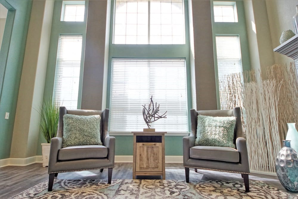 two chairs in a living room with a rug and windows