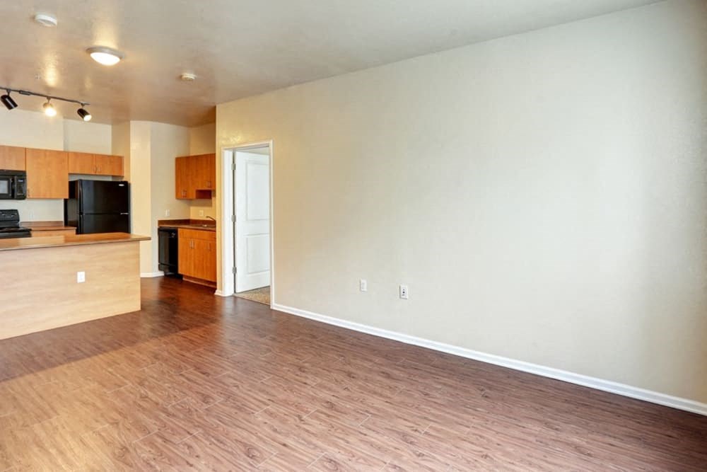 an empty living room and kitchen with wood flooring