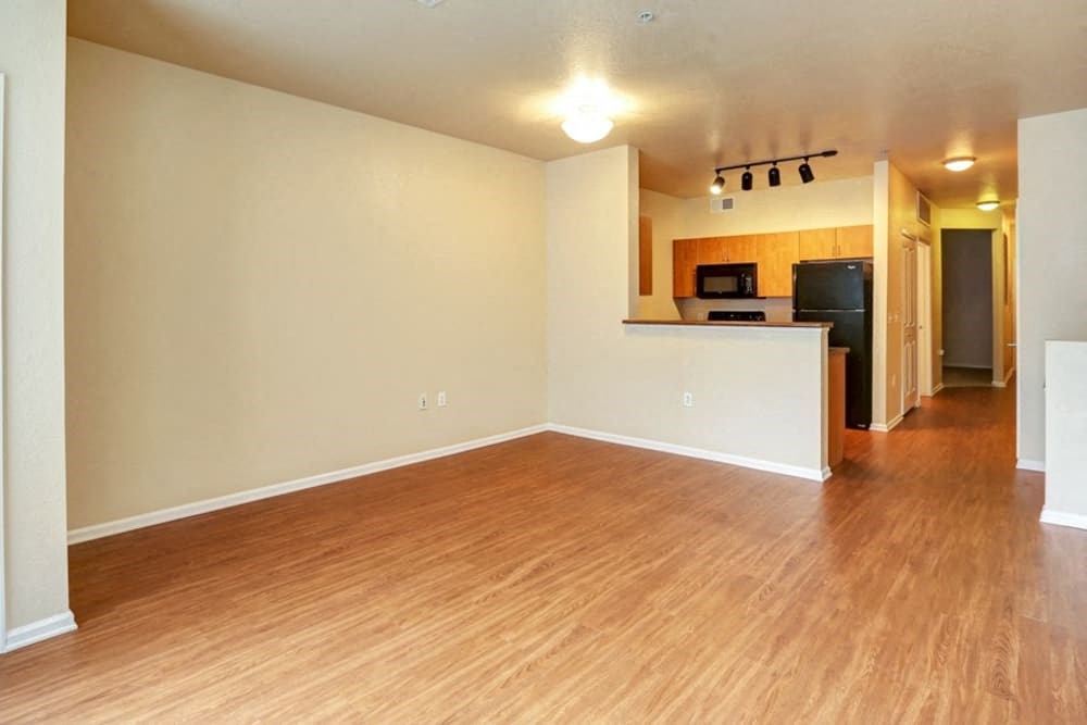 an empty living room and kitchen with wood flooring