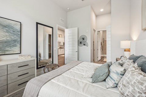 A bedroom with a large bed and a painting on the wall.