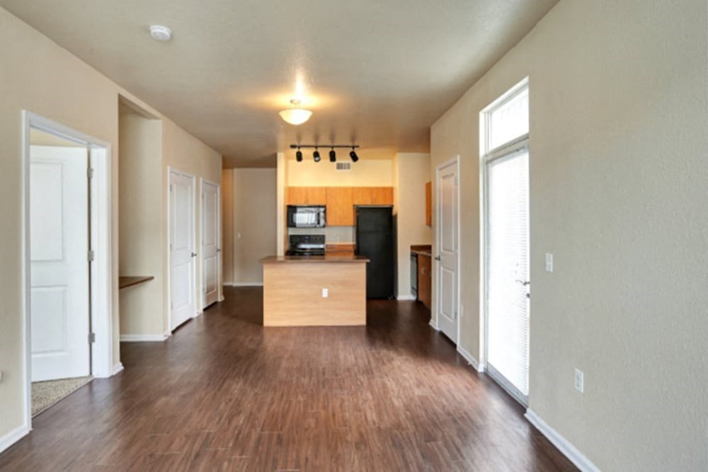 an empty living room and kitchen with wood flooring
