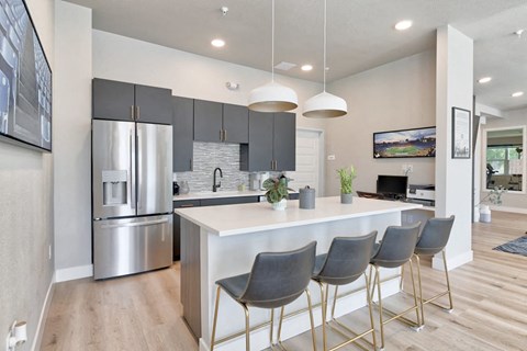 a kitchen with a large island and a stainless steel refrigerator