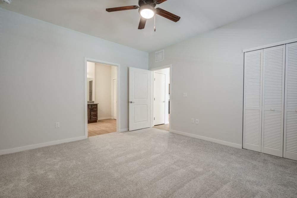 an empty living room with a ceiling fan and a closet