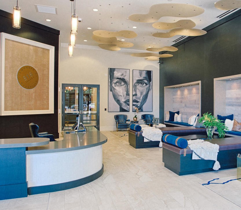 a lobby with blue couches and chairs and a large painting on the wall