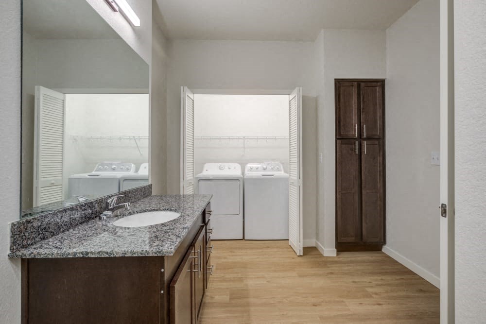 A bathroom with a sink, mirror, and washer & dryer.