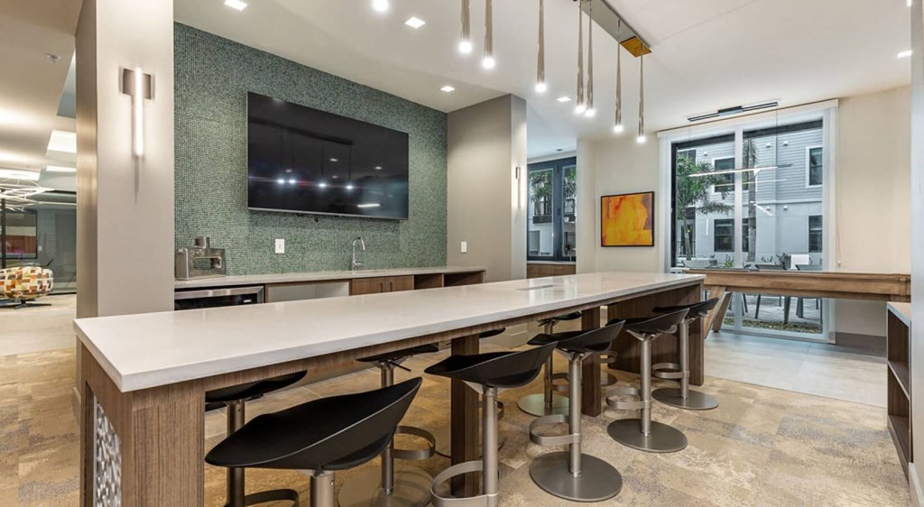 a long bar with bar stools and a tv in a lobby