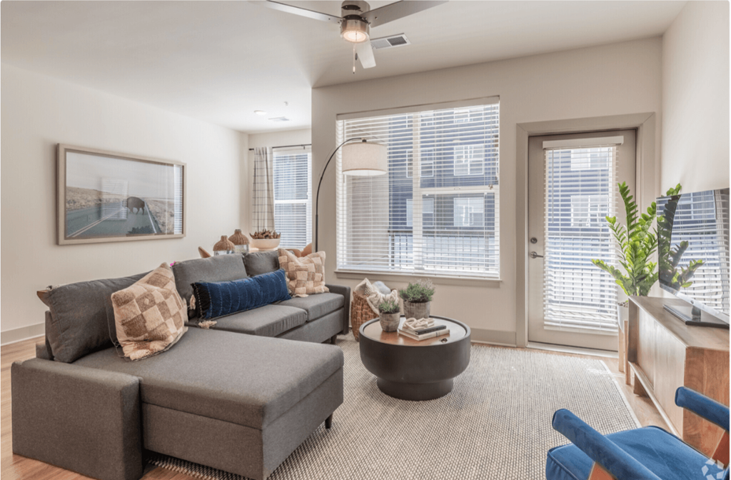 A living room with a grey couch and a ceiling fan.