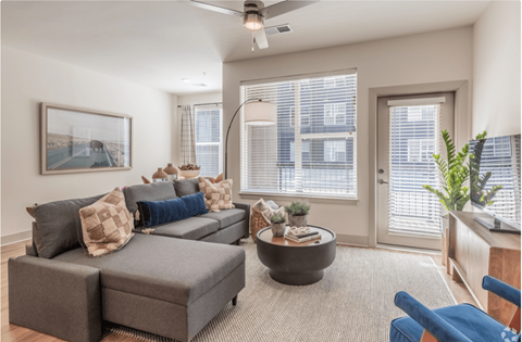 A living room with a grey couch and a ceiling fan.