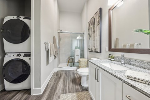 A modern bathroom with a washer and dryer built into the cabinetry.