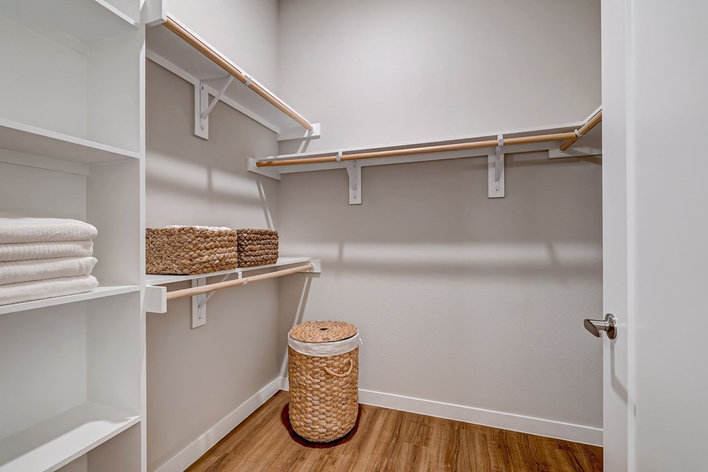A linen closet with shelves and a basket on the floor.
