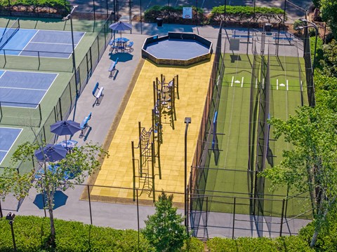 A tennis court surrounded by trees and bushes.