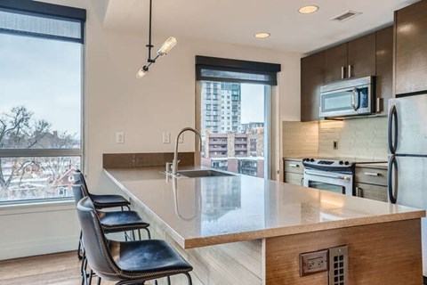 A kitchen with a long counter and a window overlooking a cityscape.