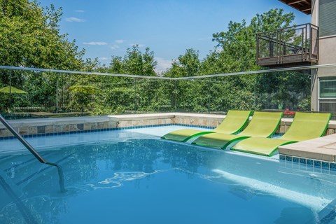 A pool with a green chair and a white fence.