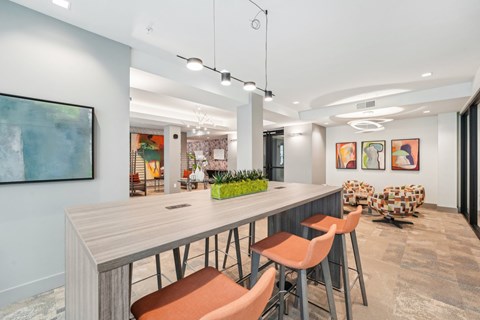 A modern dining room with a long table and orange chairs.