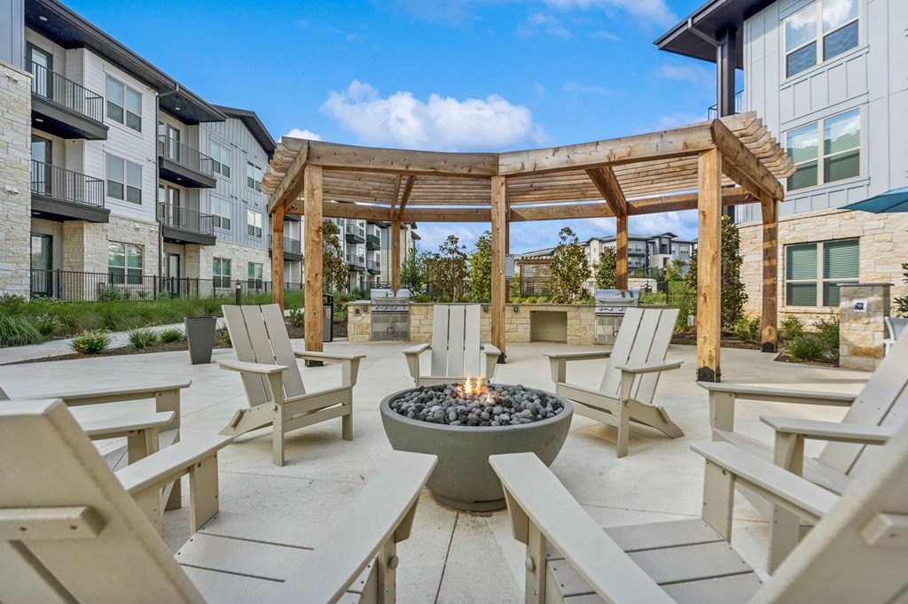 A patio with a fire pit and chairs.