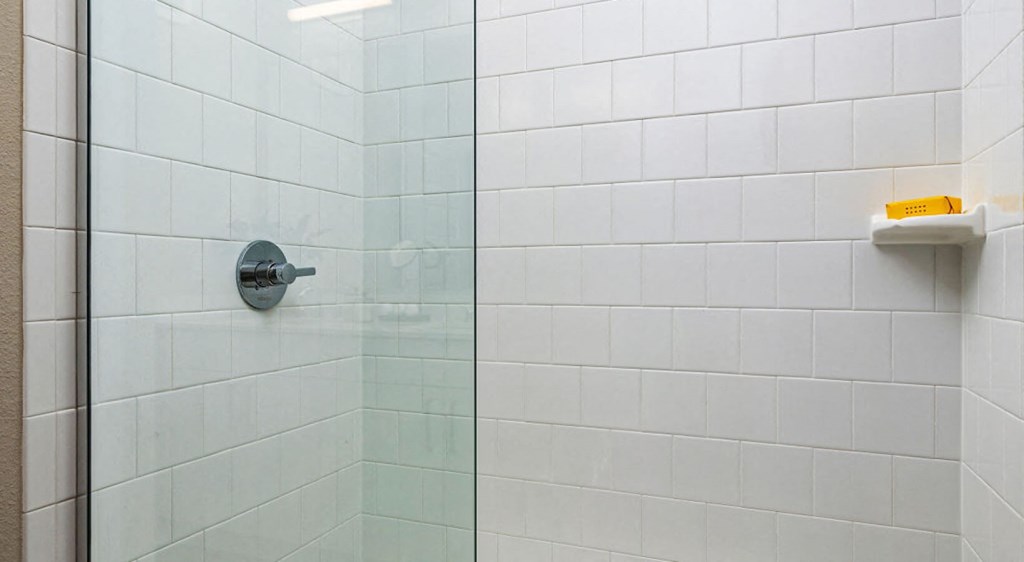a white tiled bathroom with a glass shower door