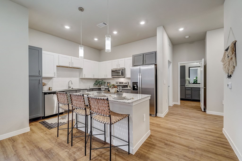 A kitchen with a white island and chairs.