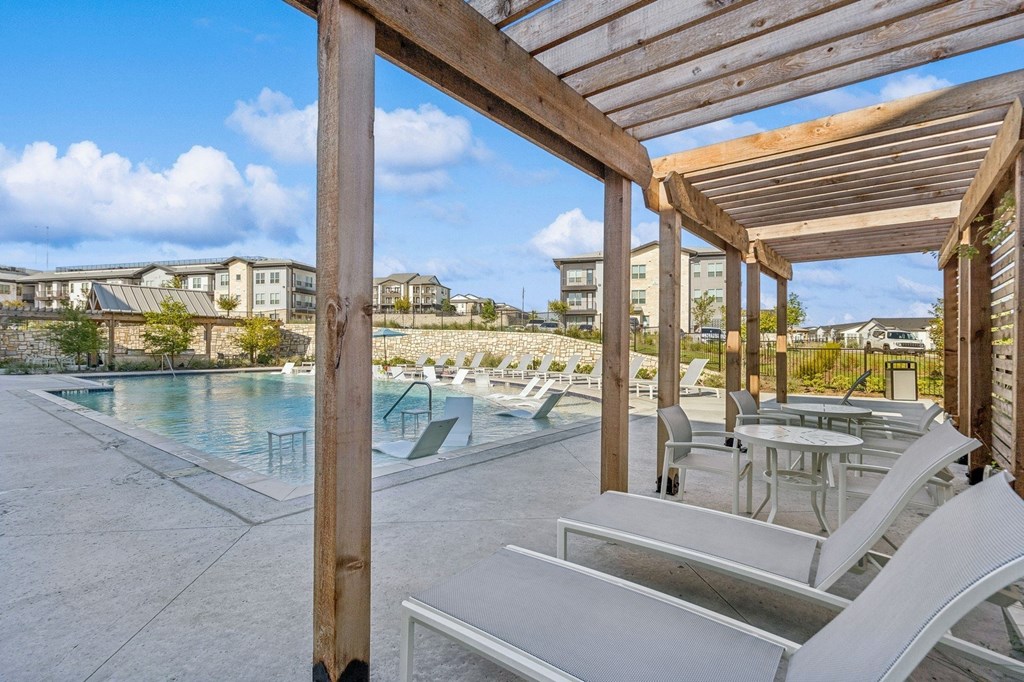 A pool area with sun loungers and a wooden pergola.