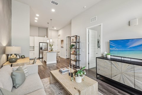 A modern living room with a grey sofa, a wooden coffee table, and a large flat-screen TV.