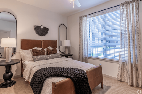 A bedroom with a large bed and a window with curtains.