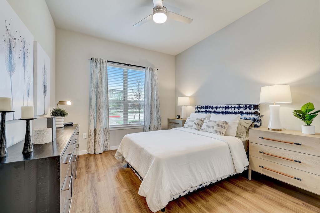 A bedroom with a large bed, a dresser, and a ceiling fan.