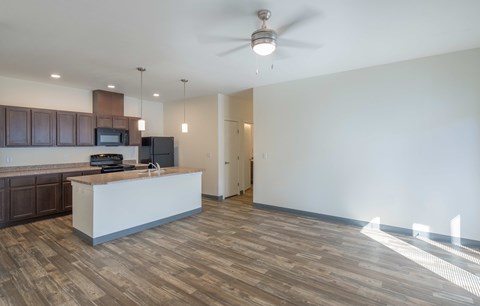 A spacious kitchen with wood flooring and a ceiling fan.