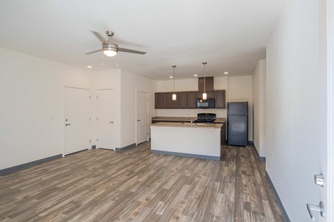A kitchen and living room with a ceiling fan and wooden flooring.