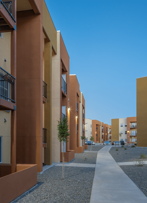 A long concrete walkway leads between apartment buildings.