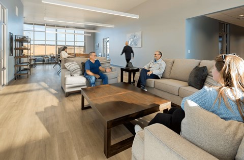 A group of people are sitting in the lounge area of the leasing office