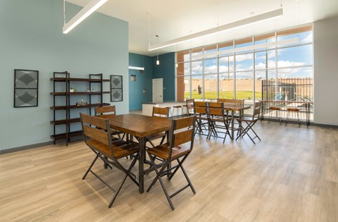 A room with a long table and chairs and a view of the outside from clubhouse