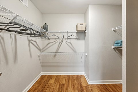 A walk-in closet with clothes hanging on hangers.