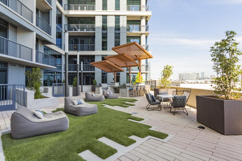 a rendering of an apartment patio with grass and furniture