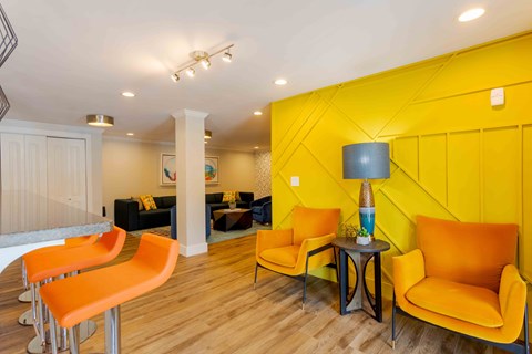 A living room with orange chairs and a yellow wall.