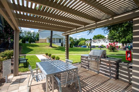 A patio with a table and chairs under a wooden pergola.