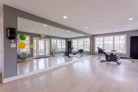 A spacious gym with exercise equipment and mirrors on the wall.