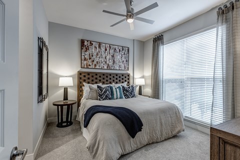 A bedroom with a large bed and a ceiling fan.