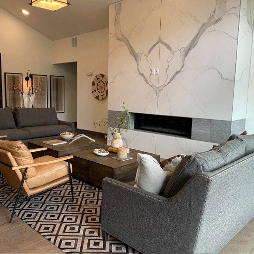 a living room with couches and chairs and a marble wall